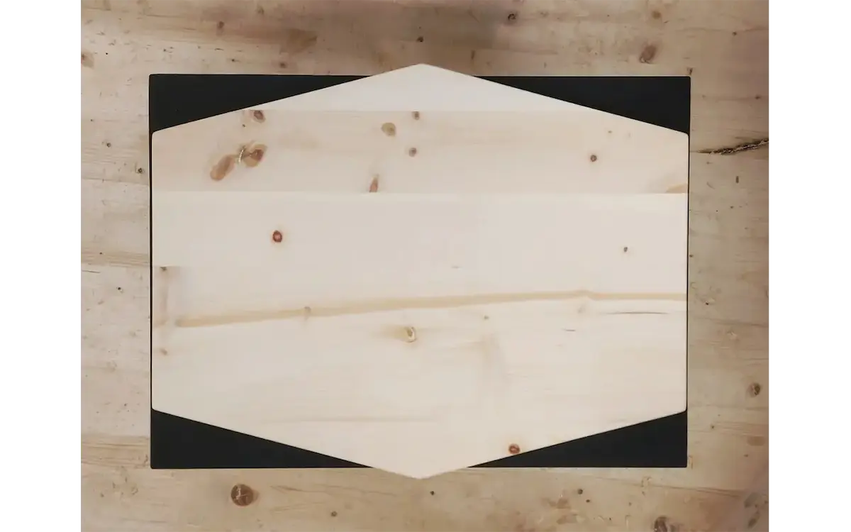 Draufsicht auf einen sechseckigen Holztisch aus hellem Fichtenholz mit schwarzer Unterlage
